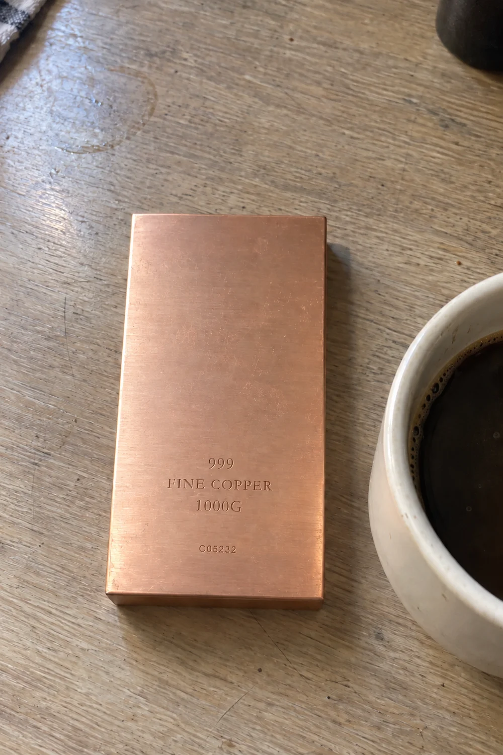 Brushed copper bar on a wooden table beside a coffee cup